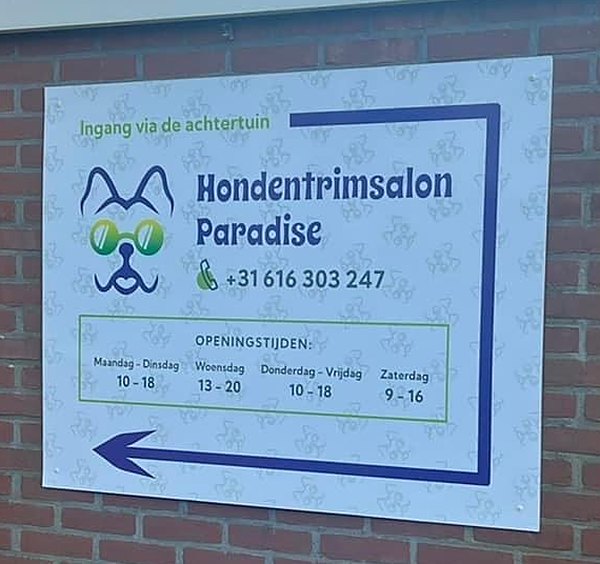 Het bord van de salon op de muur, met een pijl naar de ingang
